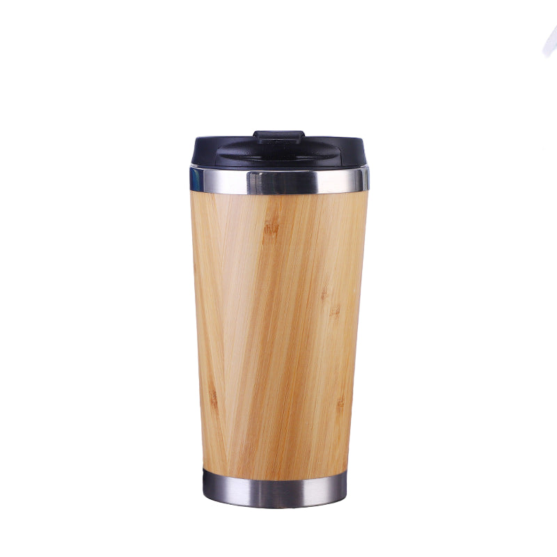 Wooden travel mug with black lid on a desk next to a laptop