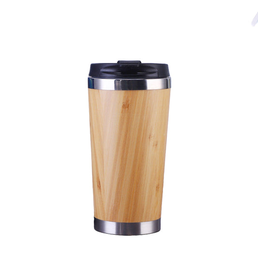Wooden travel mug with black lid on a desk next to a laptop